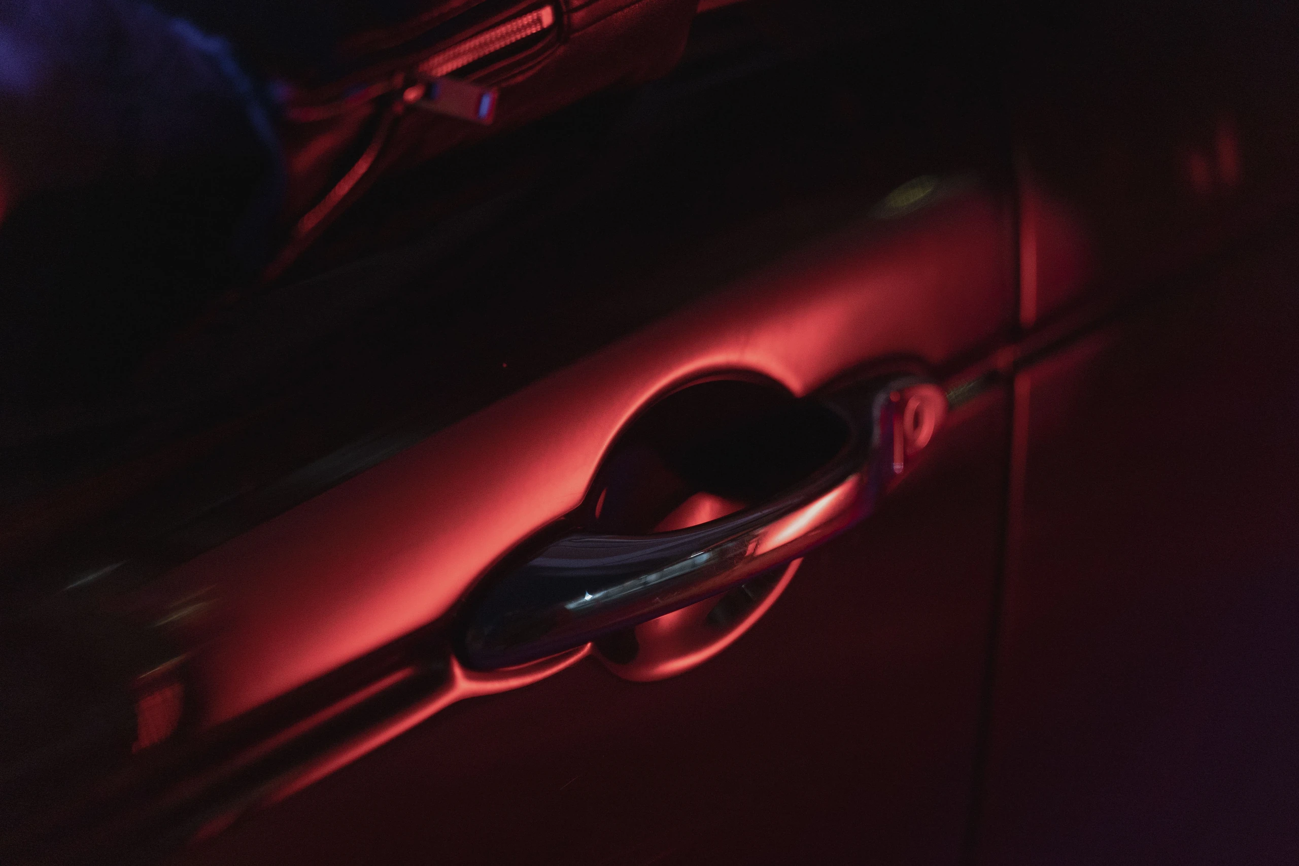 A vehicle door handle in sculpted light, presented in black and white.