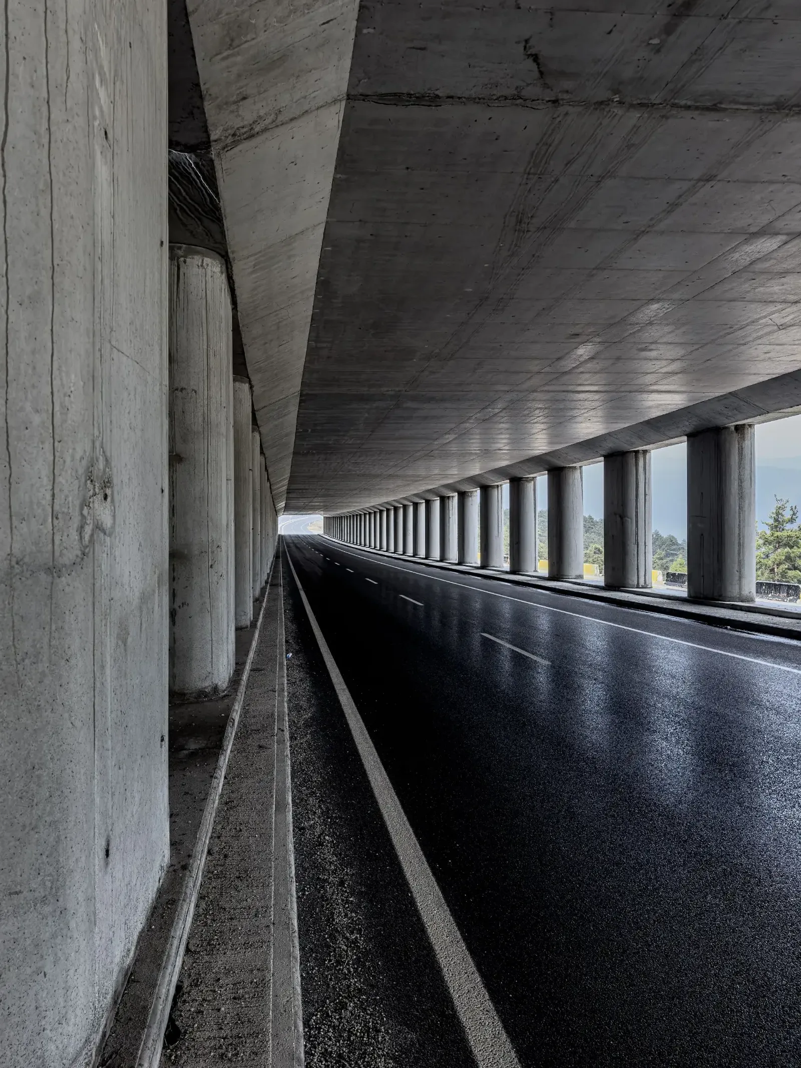 A quiet road runs beneath a colonnade of concrete pillars.