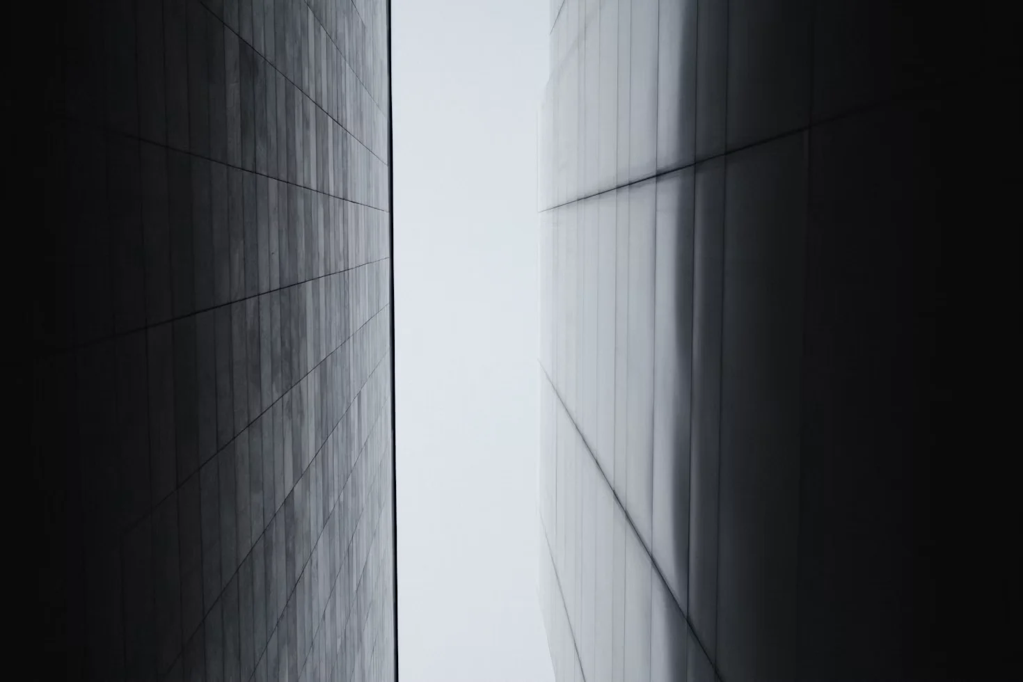 Two facades framing a narrow strip of sky, in black and white.